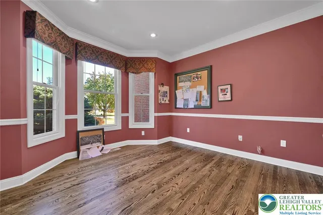 a room with wooden floor pool table and windows