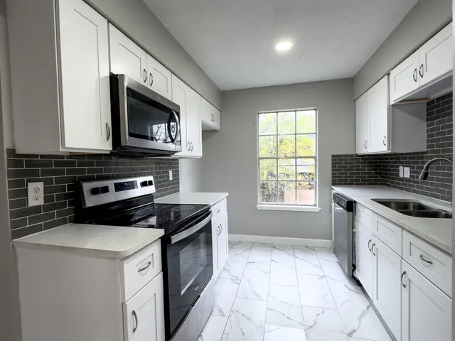 a kitchen with granite countertop a stove a sink and a microwave