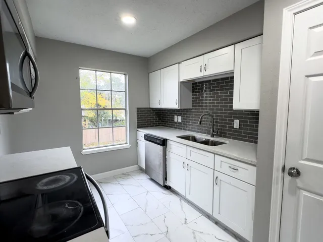 a kitchen with granite countertop a stove a sink and a microwave