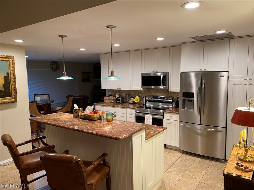 1113 Sand Castle Road Sanibel, FL 33957 - Photo 20 of 50 a kitchen with stainless steel appliances granite countertop a refrigerator a sink a stove a microwave and wooden floor
