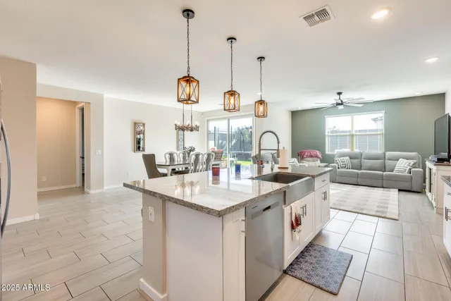 a kitchen with stainless steel appliances granite countertop a refrigerator a sink dishwasher a stove and white cabinets with wooden floor