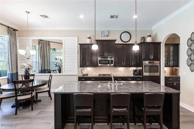 a kitchen with granite countertop a table chairs stove and wooden floor