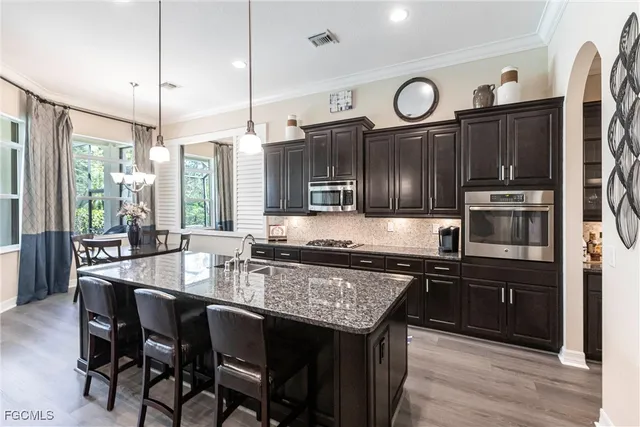 a kitchen with granite countertop a stove a sink dishwasher a dining table and chairs with wooden floor