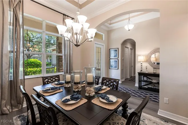 a view of a dining room with furniture a chandelier and large windows