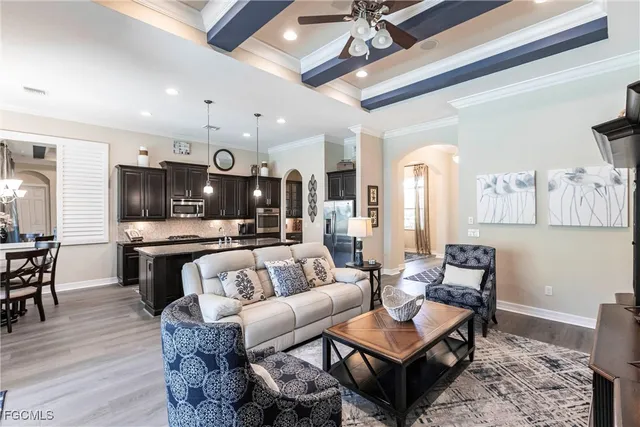 a living room with furniture kitchen view and a wooden floor