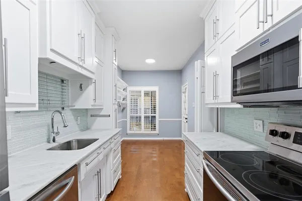 a kitchen with stainless steel appliances a sink a stove and cabinets
