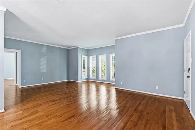 a view of an empty room with wooden floor and window