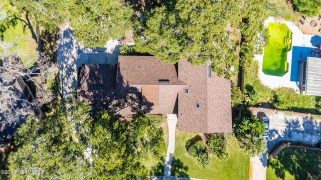 an aerial view of a house with a yard and large trees
