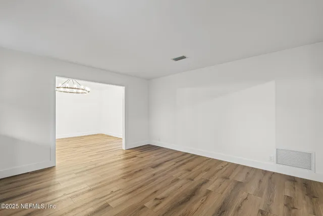 a view of an empty room with wooden floor and a fireplace