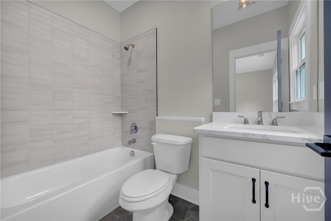 2476 St Martin Way Monroe, GA 30656 - Photo 56 of 75 Contemporary bathroom featuring a white vanity with a rectangular undermount sink, a large mirror, and a white bathtub with subway tile surround and a glass shower partition