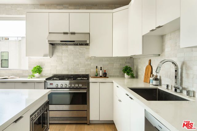a kitchen with stainless steel appliances white cabinets a stove a sink and white cabinets