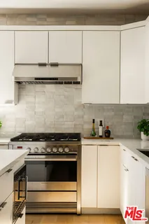 a kitchen with granite countertop a stove and a white cabinets