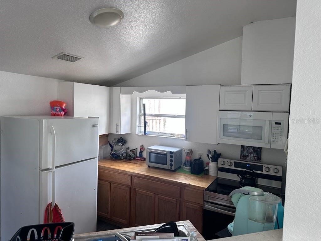 10030 Ingram Avenue Ocoee, FL 34761 - Photo 12 of 16 a kitchen with stainless steel appliances granite countertop a refrigerator sink stove and white cabinets