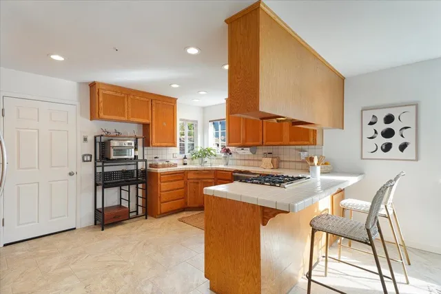 a kitchen with stainless steel appliances granite countertop a stove top oven a sink a dining table and chairs with wooden floor