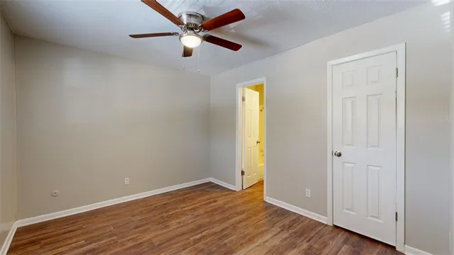 an empty room with wooden floor and a ceiling fan