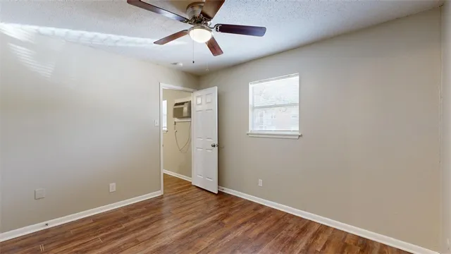 an empty room with wooden floor ceiling fan and windows