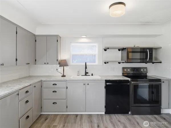 a kitchen with granite countertop a sink stainless steel appliances and white cabinets