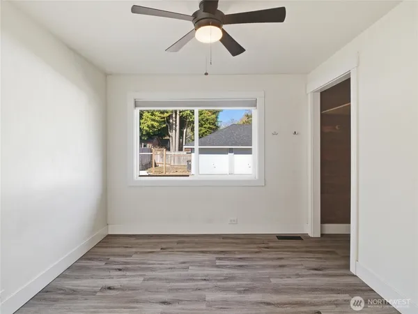 a view of empty room with wooden floor and fan