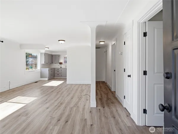 a view of a hallway with wooden floor and a bathroom
