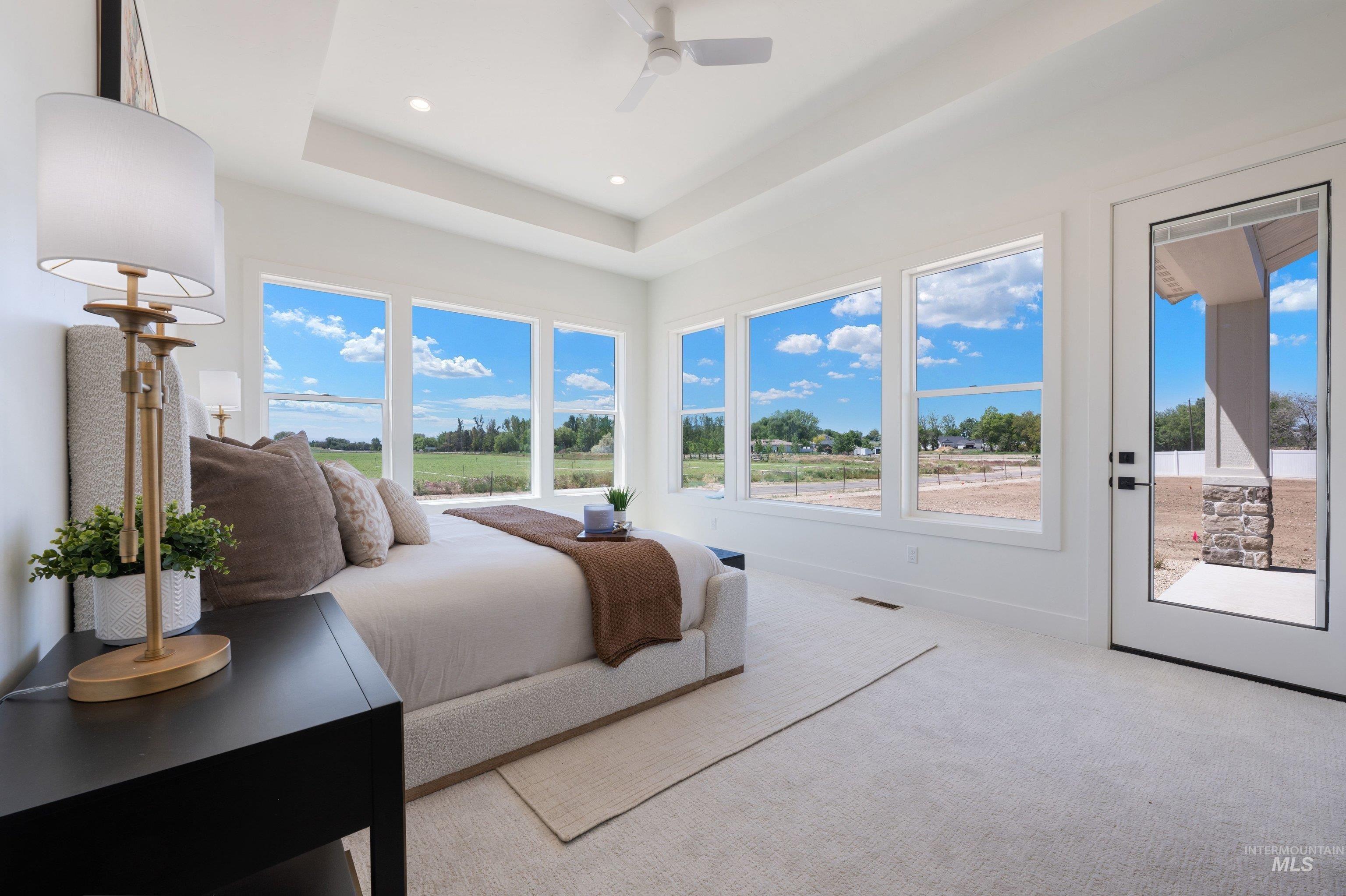 24821 Ardmore Court Caldwell, ID 83607 - Photo 37 of 43 Bright bedroom featuring multiple large windows, a tray ceiling, recessed lighting, white carpeting, and a glass-paneled exterior door