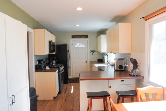 324 Stringtown Road Georgetown, ID 83239 - Photo 13 of 49 Kitchen featuring stainless steel range with gas cooktop, a breakfast bar area, dark wood-style floors, a peninsula, and white cabinets