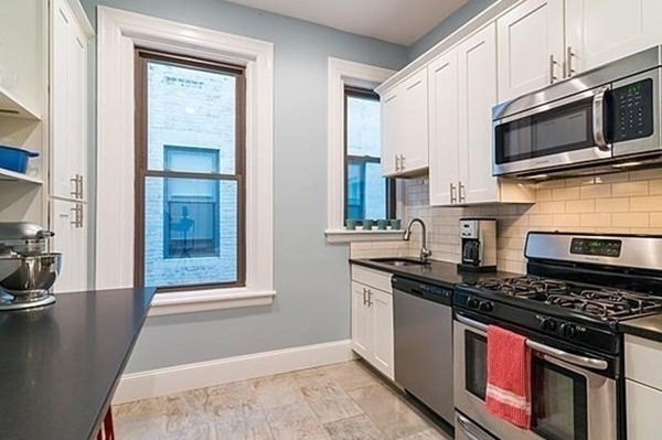 1060 Beacon Street, Unit 5 Brookline, MA 02446 - Photo 2 of 6 a kitchen with stainless steel appliances a stove a sink and a microwave
