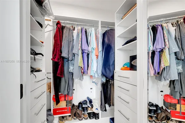 a view of walk in closet with clothes and shoes