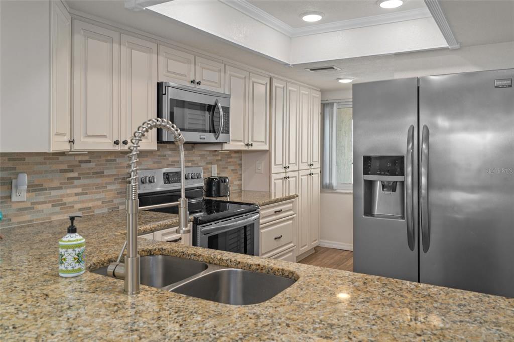 8211 Brent Street, Unit 847 Port Richey, FL 34668 - Photo 10 of 29 a kitchen with stainless steel appliances granite countertop a refrigerator and a sink