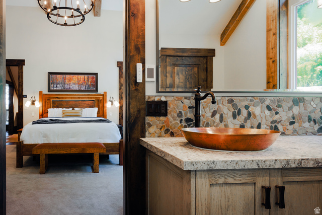 1667 West Tollgate Cyn Road Coalville, UT 84017 - Photo 29 of 61 Copper vessel sink with an oil-rubbed bronze faucet on a speckled countertop, complemented by a river rock backsplash and wood-finish cabinetry