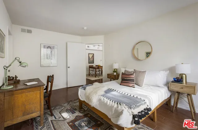 a bedroom with a bed and a dresser with wooden floor