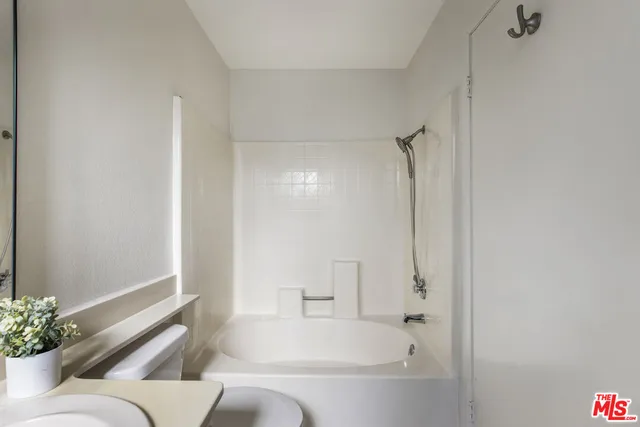 a bathroom with a tub shower and mirror