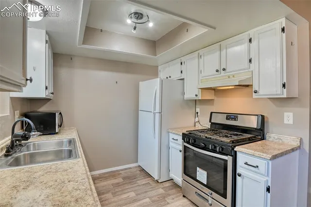 a kitchen with granite countertop a sink stove and refrigerator