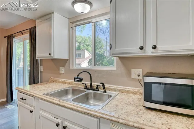 a kitchen with granite countertop white cabinets and a sink
