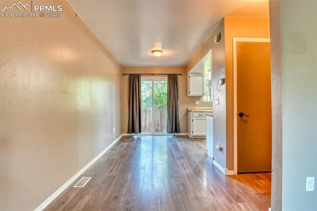 a view of a hallway with wooden floor and a kitchen