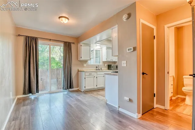 a kitchen with white cabinets and wooden floor