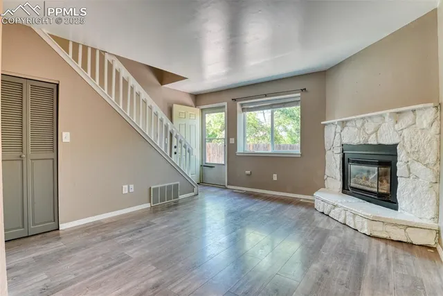 a view of an empty room with wooden floor fireplace and a window