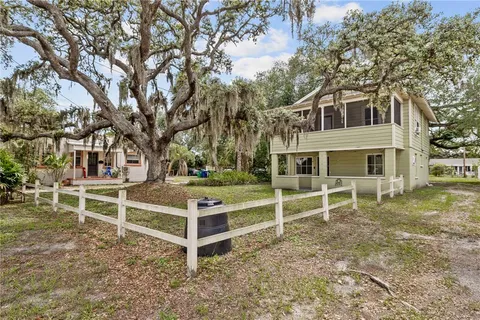 a view of a house with a yard and large tree