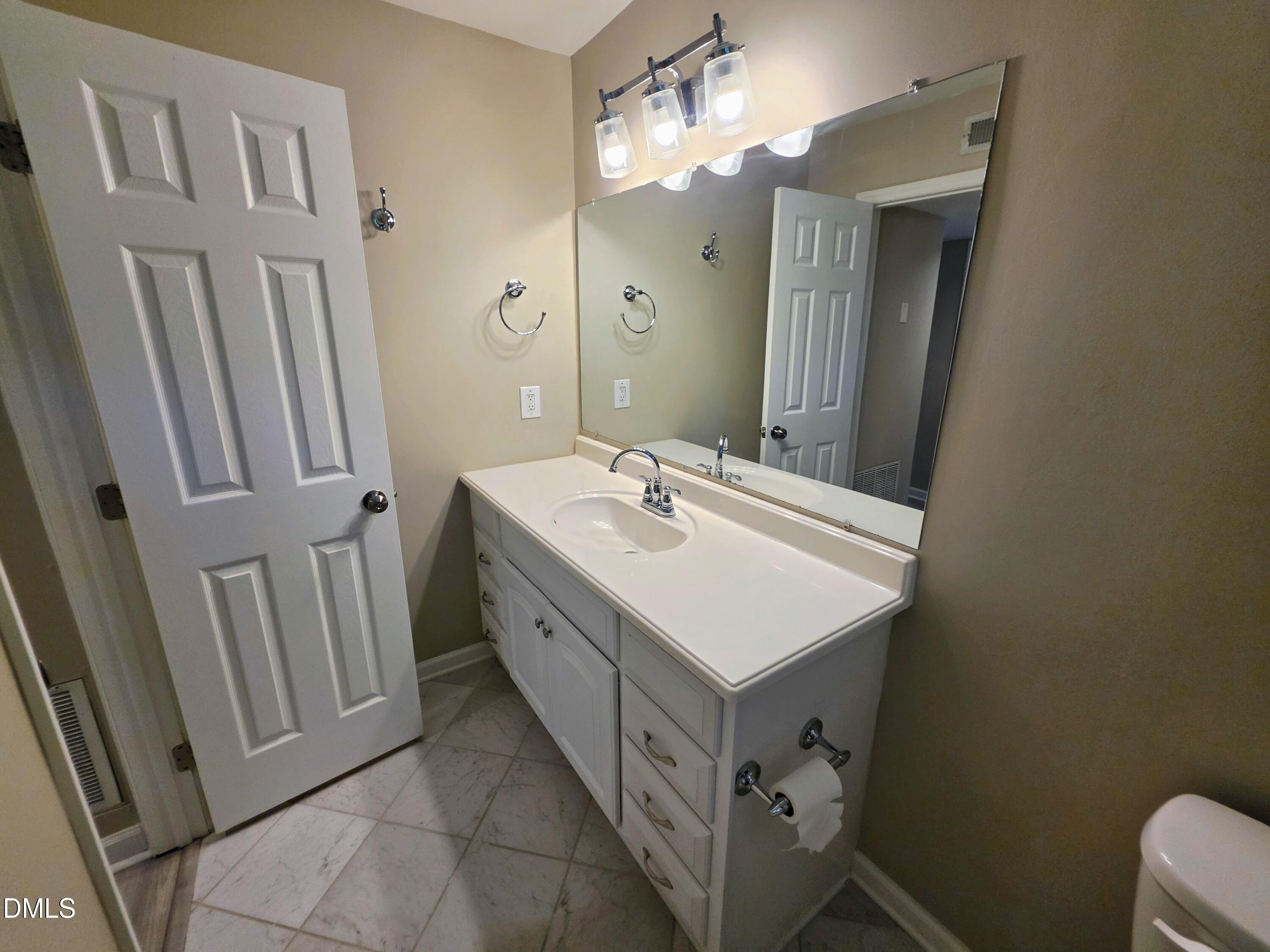 3803 Chimney Ridge Place, Unit 4 Durham, NC 27713 - Photo 10 of 16 a bathroom with a sink a toilet a mirror and vanity