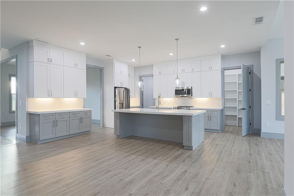 1341 Wheeler Creek Road Maysville, GA 30558 - Photo 16 of 65 a large kitchen with a wooden floor and stainless steel appliances