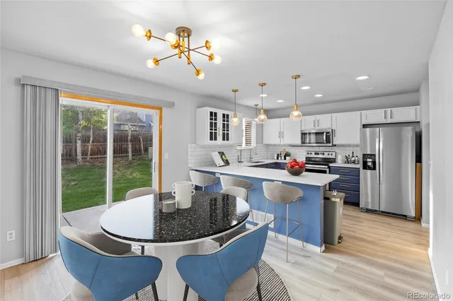 a kitchen with a dining table chairs stainless steel appliances and wooden floor