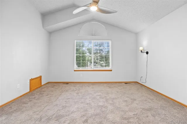 an empty room with windows and chandelier fan