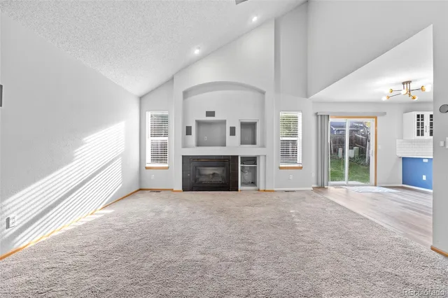 a view of an empty room with a fireplace and a window