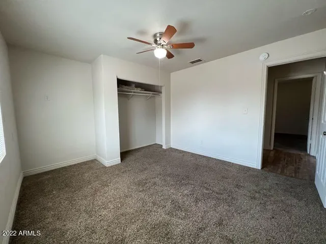 an empty room with closet and fan