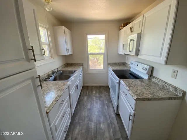 a kitchen with granite countertop a sink dishwasher stove and wood cabinets