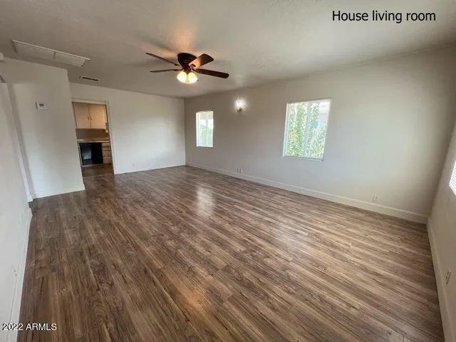 an empty room with wooden floor chandelier fan and windows
