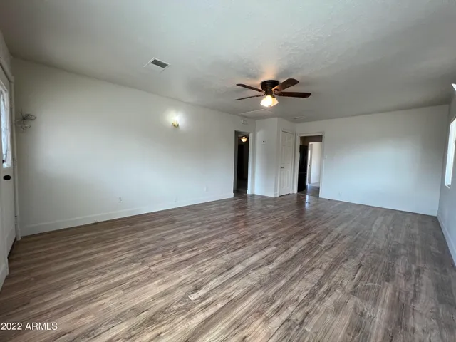 a view of an empty room with a ceiling fan and wooden floor