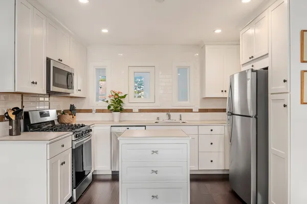 a kitchen with white cabinets and stainless steel appliances