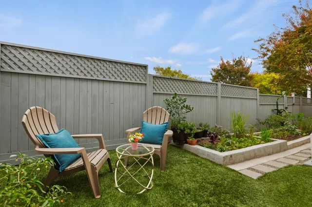 a patio with table and chairs potted plants and wooden fence