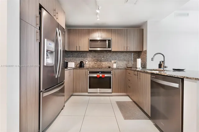 a kitchen with stainless steel appliances granite countertop a refrigerator and a sink