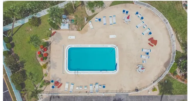 an aerial view of a swimming pool with a yard and plants